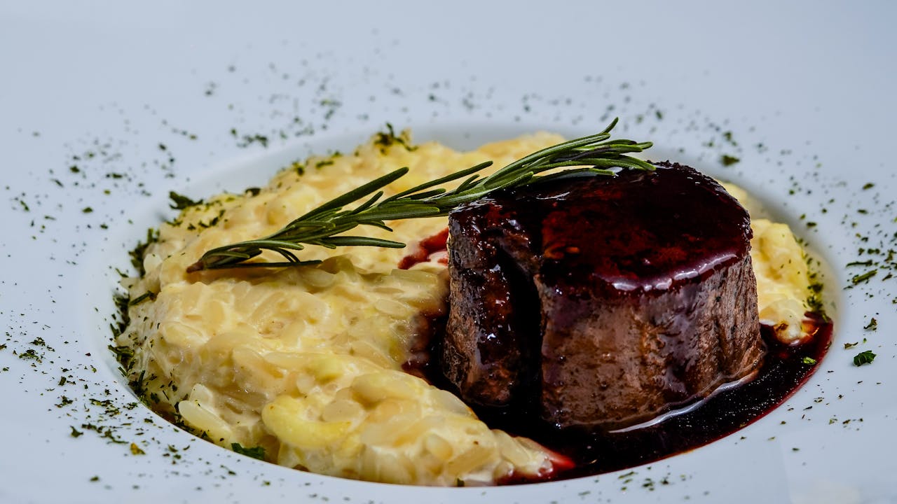 Delicious beef steak with creamy risotto and rosemary garnish, perfect for gourmet dining.